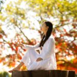 Mulher em meditação com luz solar, simbolizando clareza mental e alinhamento interno para atrair oportunidades.